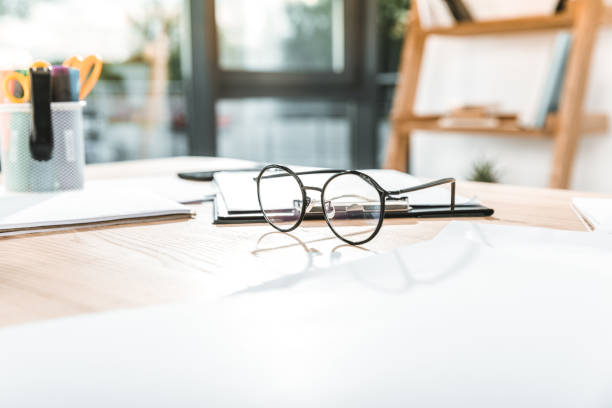 istock selective focus of round eyeglasses on workplace with papers and clipboard 1026581220