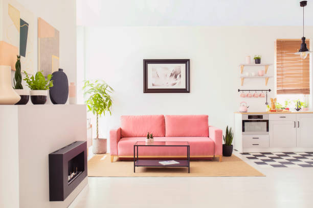 istock Poster on white wall above pink couch in flat interior with kitchenette and fireplace. Real photo 1026587132