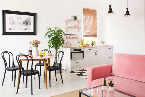 sofá cor de rosa no interior do apartamento branco com kitchenette e cadeiras pretas na mesa de jantar. foto real - studio - fotografias e filmes do acervo