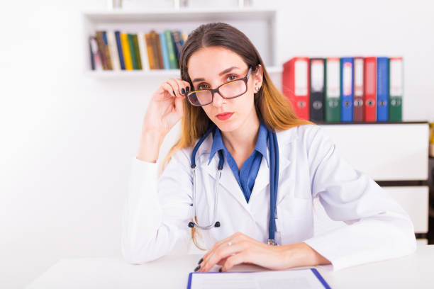 istock Young female doctor in uniform in doctor's ofice writting a document 1026592930