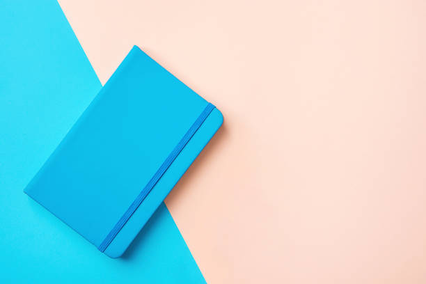 istock Business education background day planner with elastic band on duotone blue pink background. Minimalist style. Self employed businesswomen concept blog stationary sales banner. Mockup with copy space 1026594362