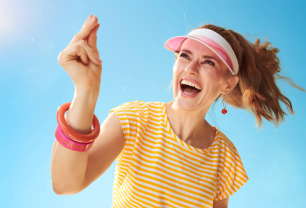 smiling young woman against blue sky fingers snapping smiling young woman in yellow shirt against blue sky fingers snapping click finger stock pictures, royalty-free photos & images