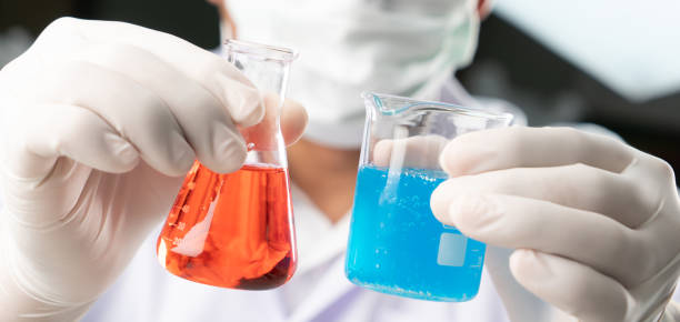 istock Chemist student boy comparing blue liquid in beger glass and erlenmeyer flask chemistry with red liquid on biochemical experiment. 1026606552