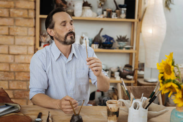 istock Mature dark-haired artist sitting at the table in his workshop 1026606920