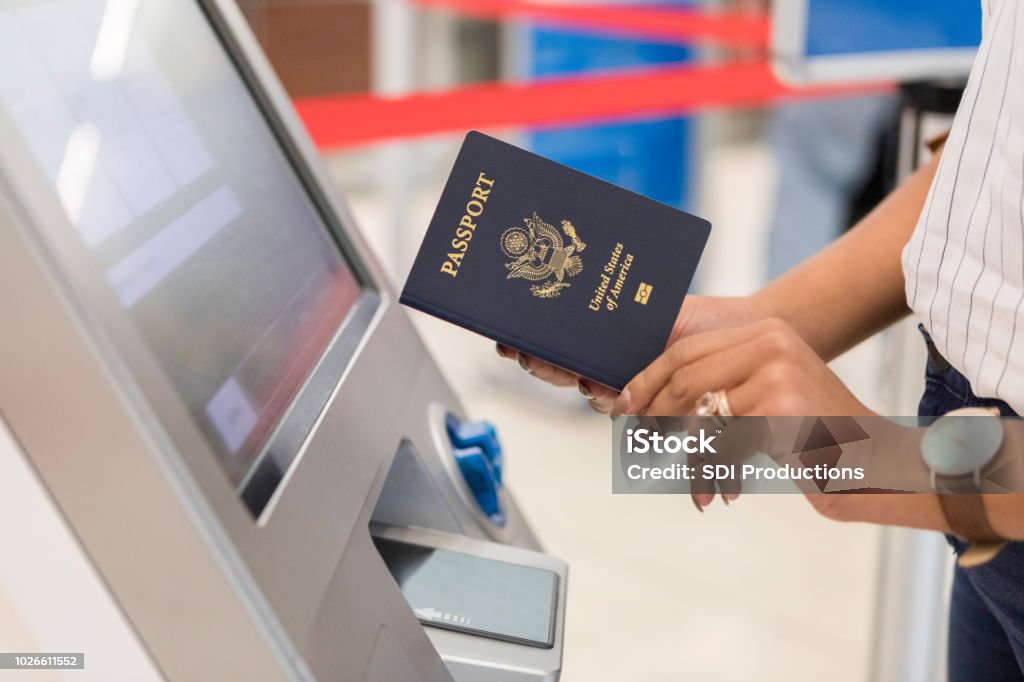 Woman uses automated passport control kiosk Unrecognizable business traveler uses an automated passport control kiosk at an international airport. Passport Stock Photo