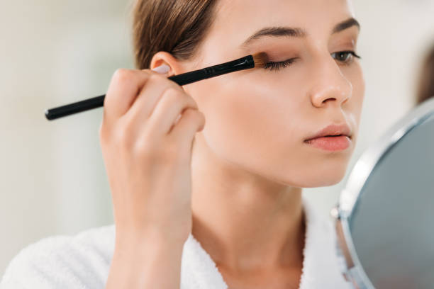 close-up view of beautiful young woman applying eyeshadow with brush close-up view of beautiful young woman applying eyeshadow with brush eyeshadow stock pictures, royalty-free photos & images