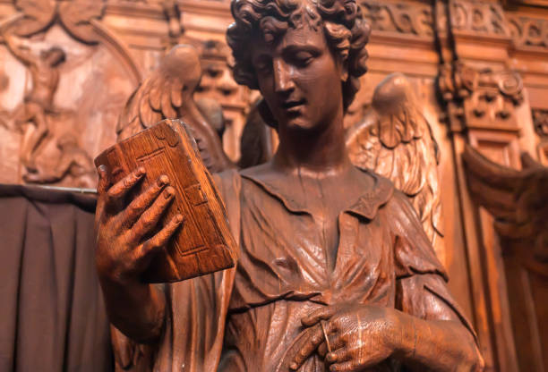 Reading angel holding an old book, wooden statue in 17th century catholic church Saint Charles Borromeo in Antwerp Antwerp, Belgium - March 30, 2018: Reading angel holding an old book, wooden statue in 17th century catholic church Saint Charles Borromeo on March 31, 2018. Near 1,200,000 people lives in Antwerp bible art library stock pictures, royalty-free photos & images