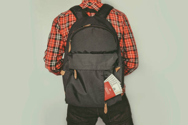 passport showing in back pocket of jeans a man with a small backpack holding the belt. Confident traveller man. passport showing in back pocket of jeans. spending on tourist trips. hand Luggage jeans denim passport pocket stock pictures, royalty-free photos & images