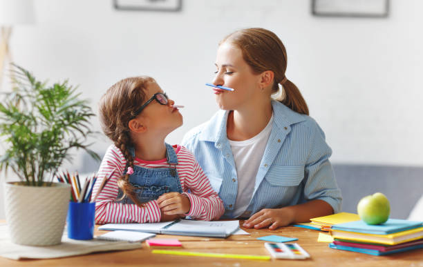 funny mother and child daughter doing homework writing and reading