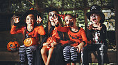 happy Halloween! a group of children in suits and with pumpkins in forest