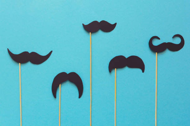 Paper mustache on booth props on blue paper background. Cut out style. Movember  or man health concept. Top view. Flat lay. Copy space. Toned Paper mustache on booth props on blue paper background. Cut out style. Movember  or man health concept. Top view. Flat lay. Copy space. Toned moustache stock pictures, royalty-free photos & images