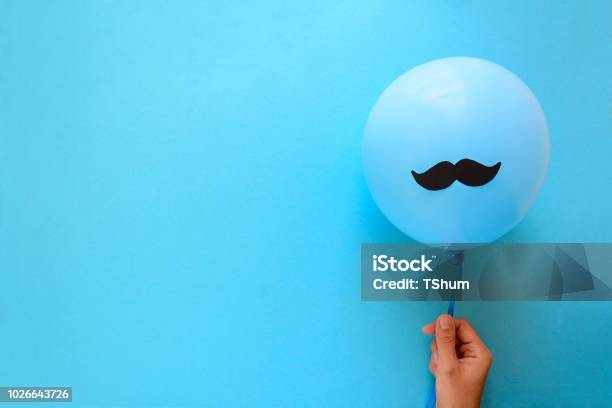 Foto de Mão Segurando O Balão Azul Com Um Bigode De Papel Com Fundo De Papel Azul Corte O Estilo Conceito De Saúde Movember Ou Homem Vista Superior Plano De Leigos Espaço De Cópia e mais fotos de stock de Homens