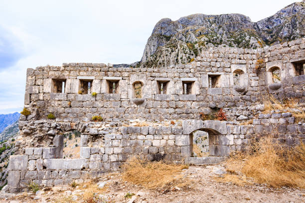Kotor, Montenegro - September 07, 2016: Mediterranean landscape. Old stone walls of medieval fortification, town ruins against Lovcen mountain in Kotor, Montenegro. Travelling to historical sites.
