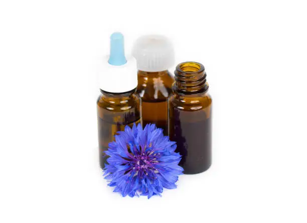 herbal essential oil in glass bottles with blue organic flower isolated on white background