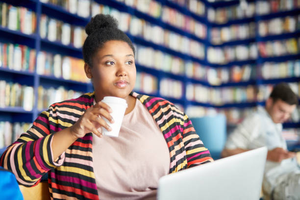 istock Woman has coffee break at library 1026660172