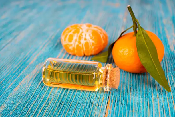 tangerine essential oil with fruits on turquoise wooden table