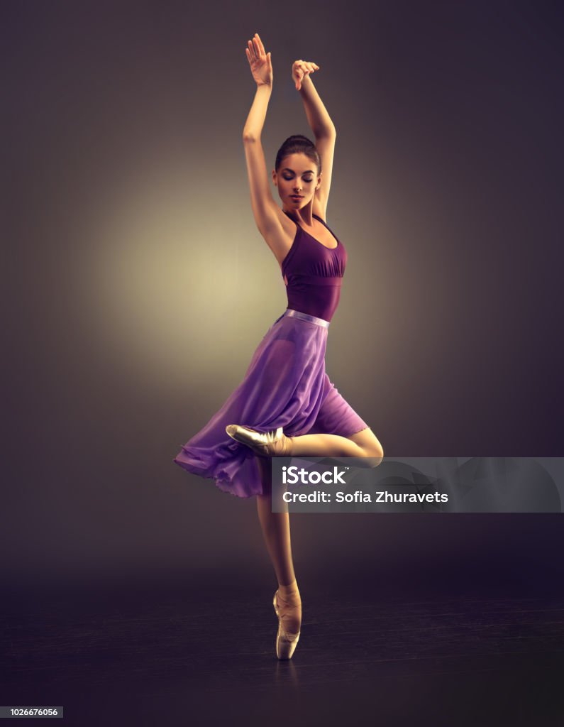 Beauty of classic ballet. Ballerina is performing classic dance. Ballerina. Young graceful woman ballet dancer, dressed in professional outfit, shoes and violet weightless skirt is demonstrating dancing skill. Beauty of classic ballet. Ballet Dancer Stock Photo