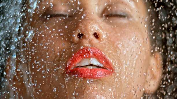 istock Close-up of woman being splashed with water 1026679714