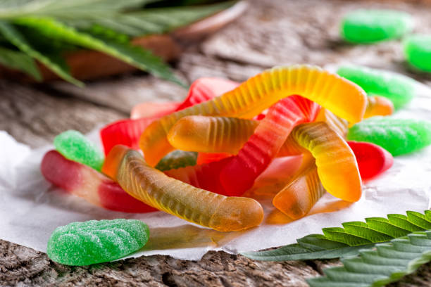 Cannabis Infused Gummy Candy Cannabis infused gummy candy on a rustic table top with marijuana leaves. gummy candy photos stock pictures, royalty-free photos & images