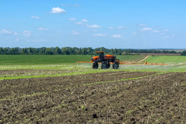 istock self-propelled sprayer works on a field under a blue sky with clouds 1026684194