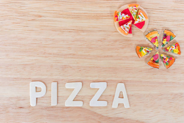 Miniature clay pizza and wooden white word PIZZA on wooden board background (overhead shot)