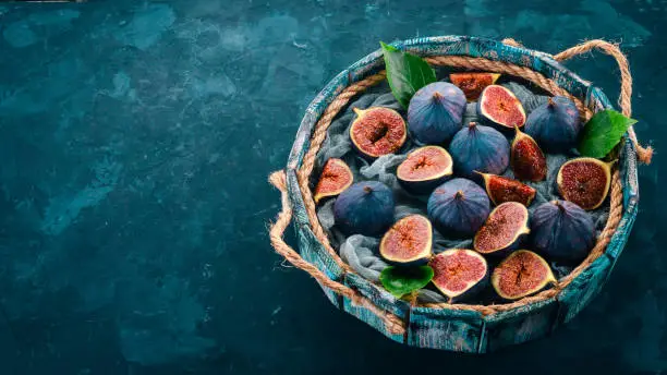 Fresh figs in a wooden box on a blue background. Free space for text. Top view.