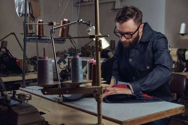 istock Making clothes. tailor sitting at table and working on a sewing machine at the sewing workshop. 1026698960