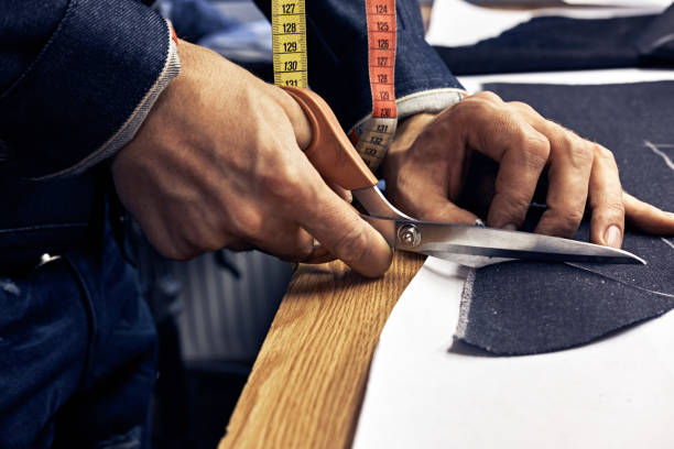 istock Close-up image of a tailor cutting dark cloth at sewing workshop. 1026701352