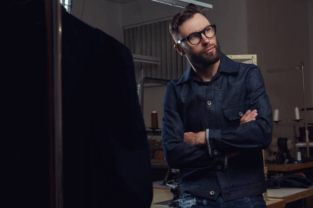 istock Tailor standing near table with sewing machine and looking away at a sewing workshop. 1026701382