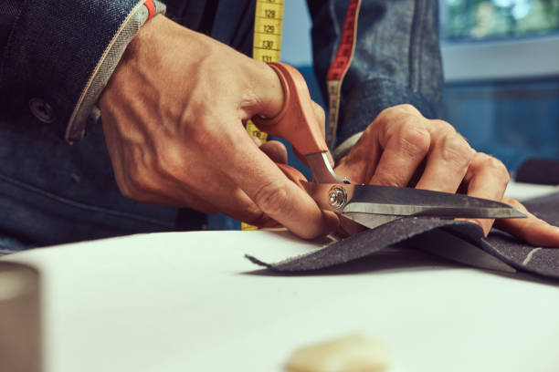 istock Close-up image of a tailor cutting dark cloth at sewing workshop. 1026701700