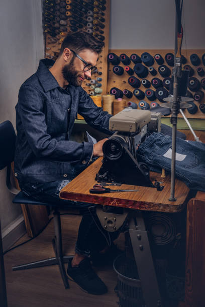 istock Making clothes. tailor sitting at table and working on a sewing machine at the sewing workshop. 1026702144