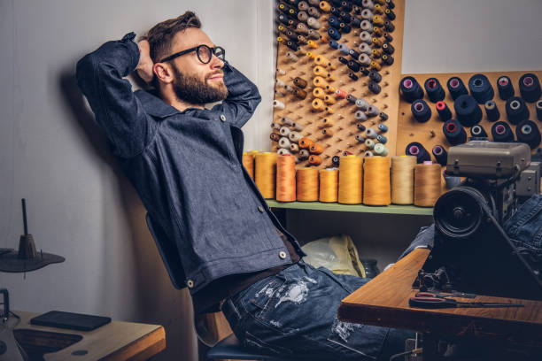istock Handsome bearded fashion designer taking a break from work and thinking about new designs in a sewing workshop. 1026702256
