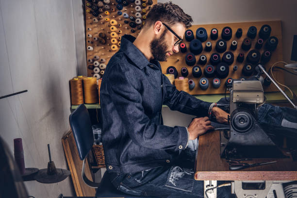 istock Making clothes. tailor sitting at table and working on a sewing machine at the sewing workshop. 1026702342