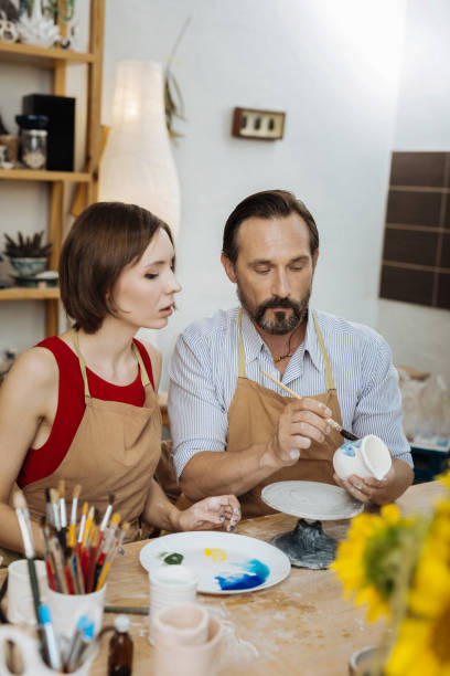 istock Dark-haired woman watching a professional ceramist working 1026705126
