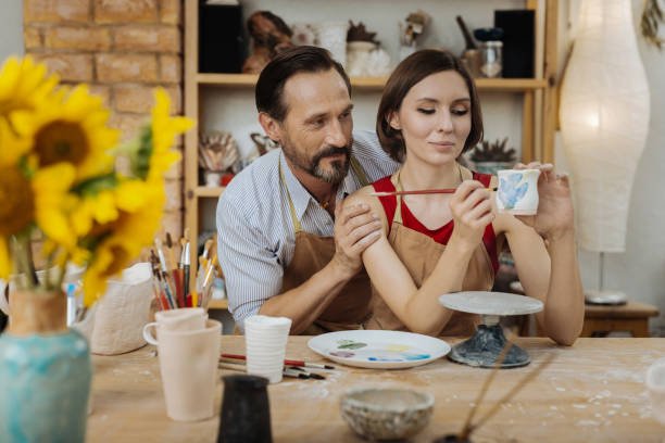 istock Bearded man supporting his wife working with clay pot 1026705484