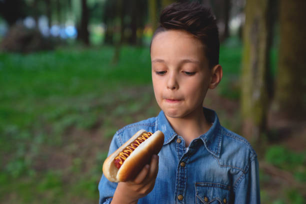 istock a young boy takes a bite of a hot dog 1026709140