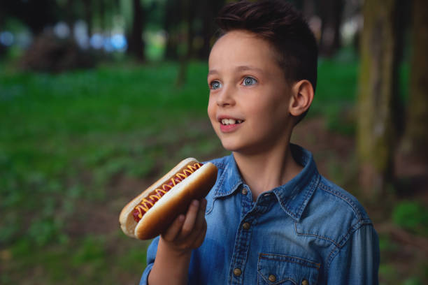 istock a young boy takes a bite of a hot dog 1026709196