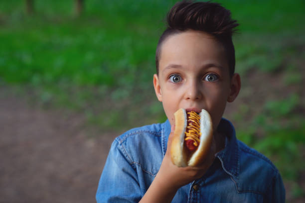 High quality stock photo of an mixed race boy with a hotdog at a summer time party.
