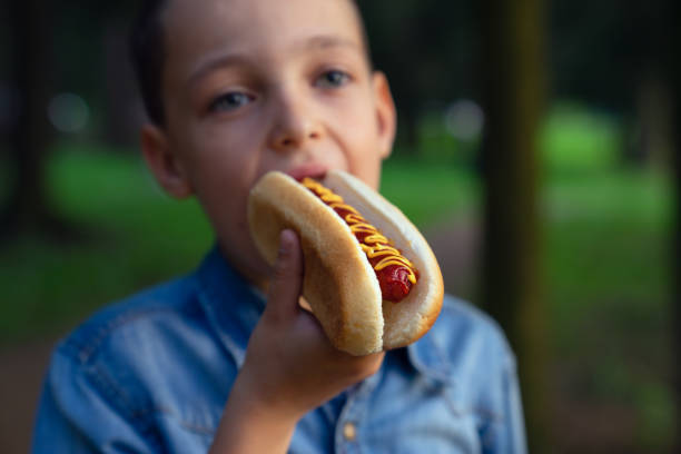 istock a young boy takes a bite of a hot dog 1026709372