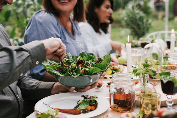 amici che si godono una cena insieme in una festa di raccolta in serra - food people close up outdoors foto e immagini stock