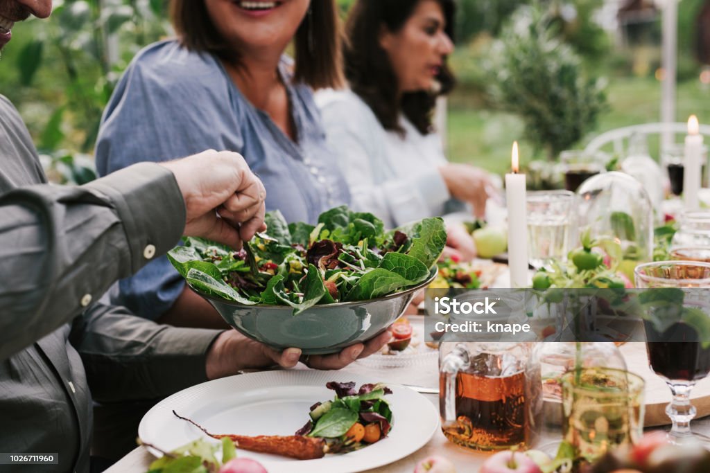 Friends enjoying a dinner together in greenhouse harvest party Friends enjoying a dinner together in greenhouse harvest party
People dining together healthy salad and nice vegetables Outdoors Stock Photo