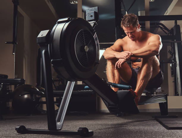 istock Muscular shirtless athlete resting after a hard workout while sits on the rowing machine in the gym. 1026713568