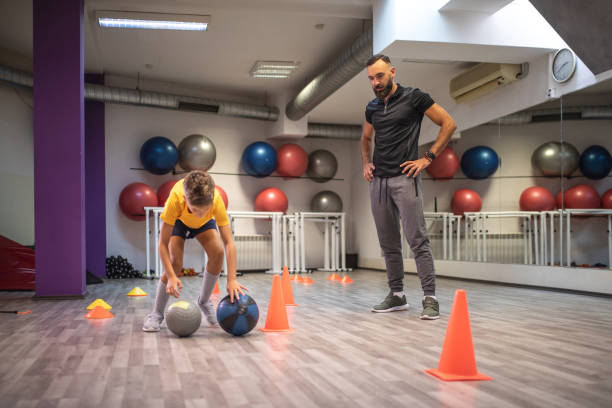 istock Child training with medicine balls supervised by his father 1026713636