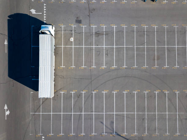 istock A long truck in a parking lot with markings for loading with building materials with sharp shadows on a sunny day 1026719134