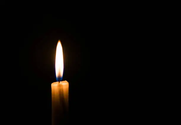 Photo of Candle light flame against black background. Concept of memory, remembrance, mourning, grief, and sorrow.