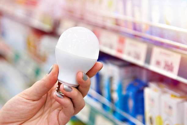 energy saving led lamp in hands of buyer at store - light shop imagens e fotografias de stock