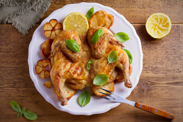 istock Whole chicken on toasted bread with lemon, basil and garlic on white plate, wooden table 1026754096