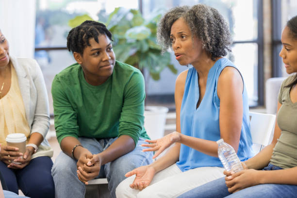 Female counselor advises people during support group meeting Confident counselor gives advice to teenagers and their parents. serious black teen stock pictures, royalty-free photos & images