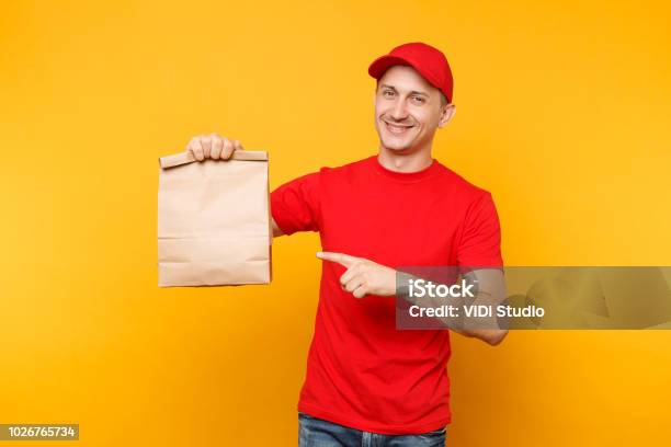 Photo libre de droit de Homme À La Casquette Rouge Donnant Ordre De Fastfood Tshirt Isolé Sur Fond Jaune Courrier De Salarié Tenir Paquet De Papier Vide Avec De La Nourriture Livraison Des Produits De La Boutique Ou Restaurant À Domicile Copiez Lespace banque d'images et plus d'images libres de droit de Livraison