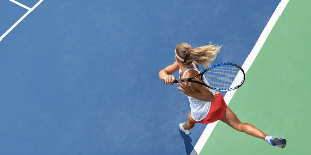 Abstract Top View Of Female Tennis Player After Serve A top view of a professional female tennis player having just served the ball during a tennis match. The athlete wears a white tennis top with red skirt, and is playing on a tennis court with a blue and green hard surface in hot and sunny conditions during the day. athletes stock pictures, royalty-free photos & images